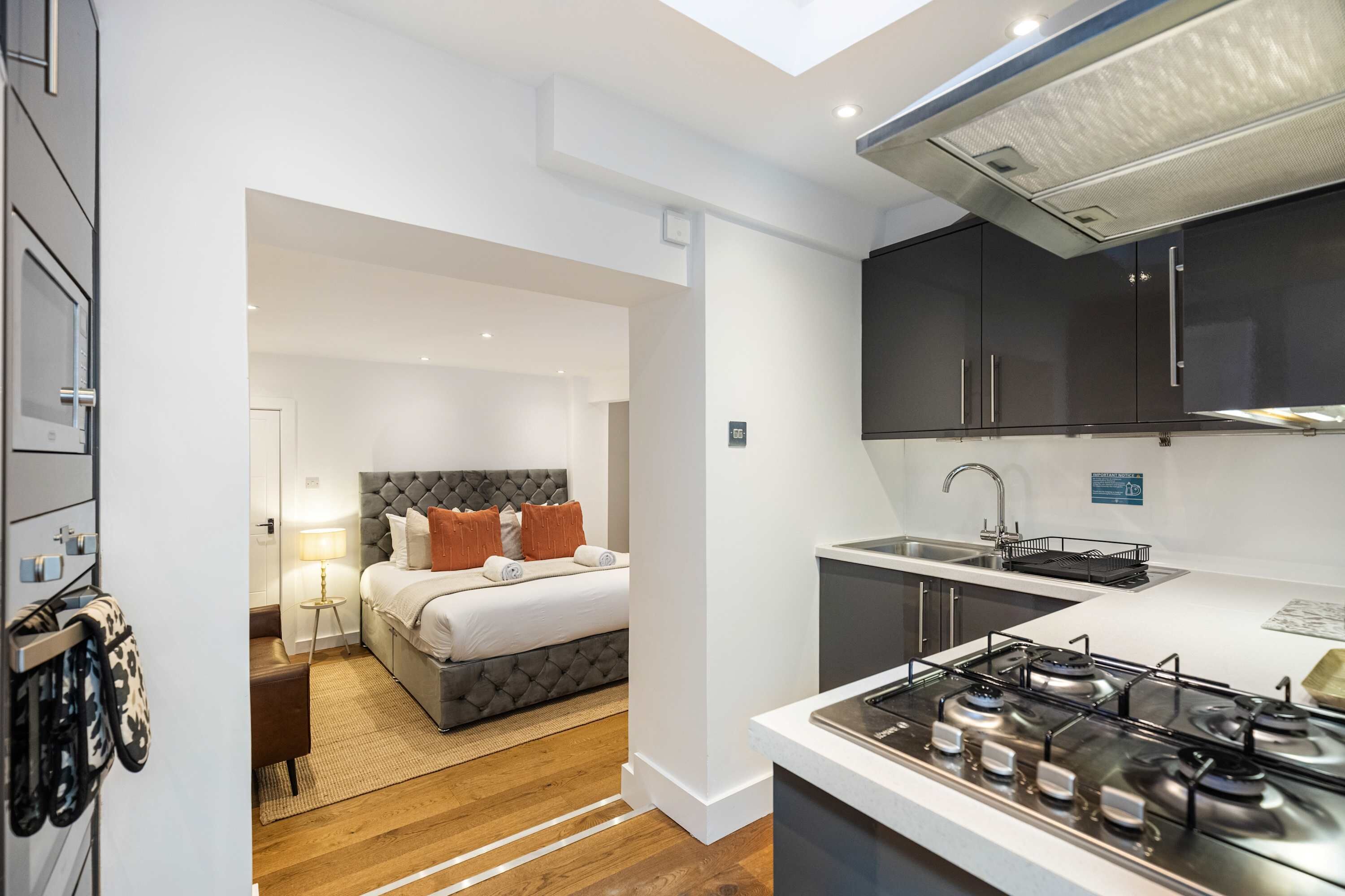 A compact hotel room with a bed, a small kitchenette, and a bathroom.