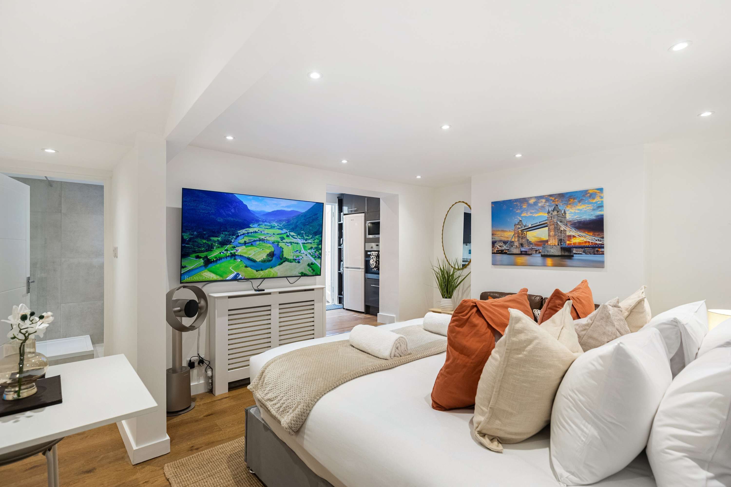Une chambre moderne avec un grand lit, un téléviseur à écran plat et un tableau représentant un pont.