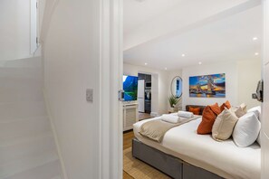 A modern bedroom with a bed, a TV, and a painting of a bridge. - Primrose Hill 1BR Flat - Private Patio (Greater London)