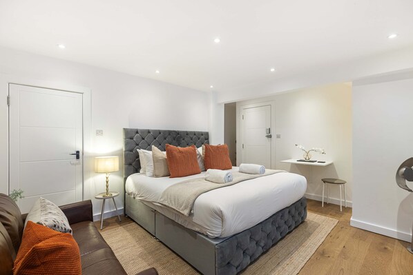 Een moderne slaapkamer met een groot bed, nachtkastjes, een bureau en een stoel.