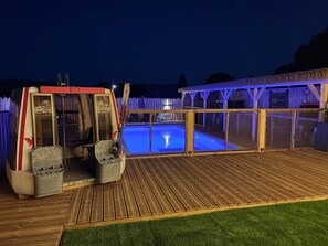 Eine Holzterrasse mit Pool, einer überdachten Sitzgruppe und einer Seilbahn.
