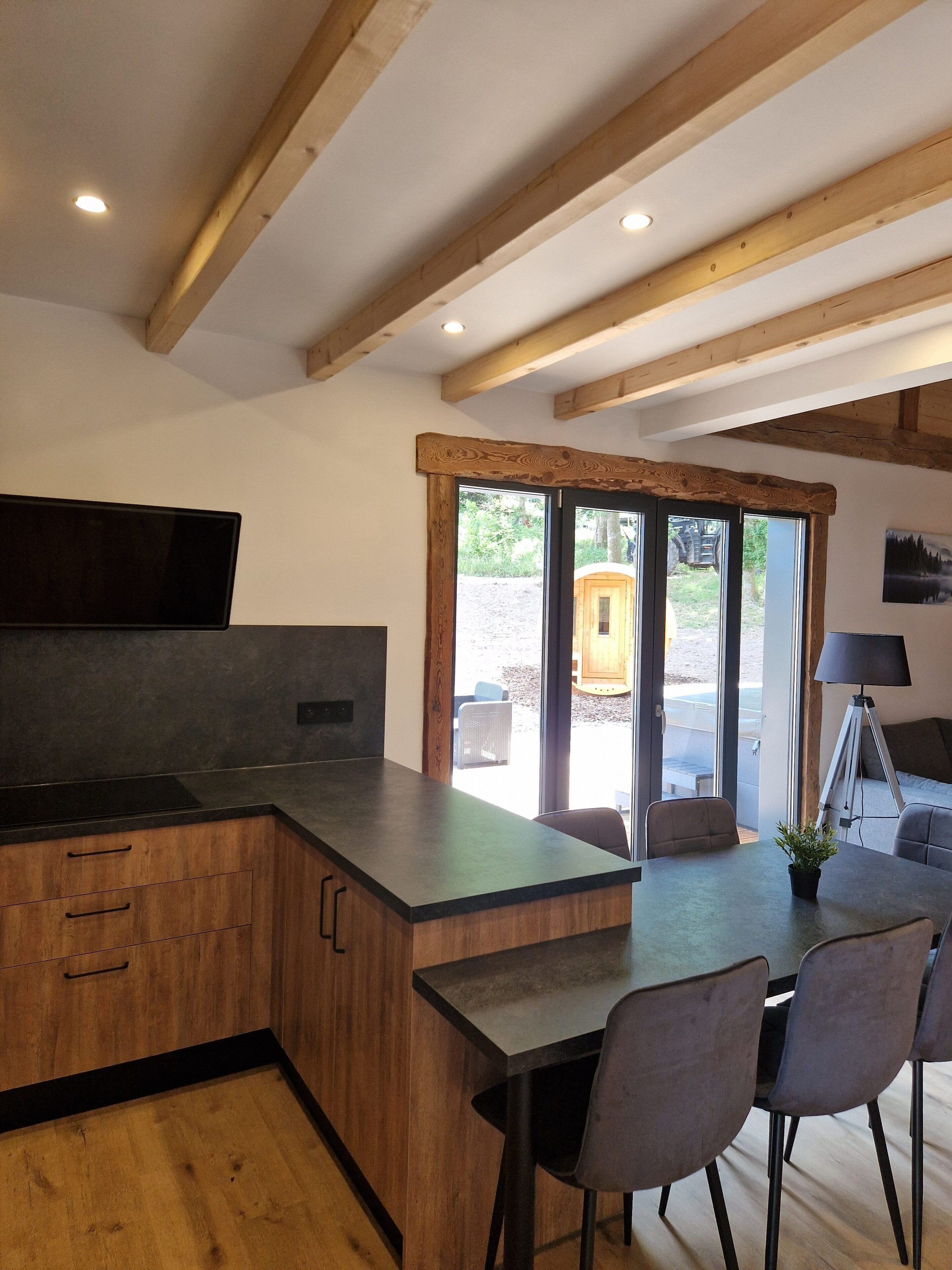 A modern kitchen with wooden cabinetry, a built-in stove, and a dining area with a table and chairs.