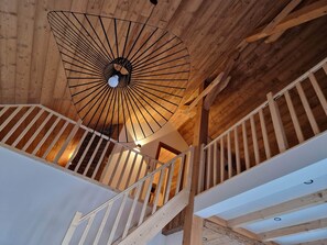 Een houten interieur met een spiltrap en een plafondlamp.