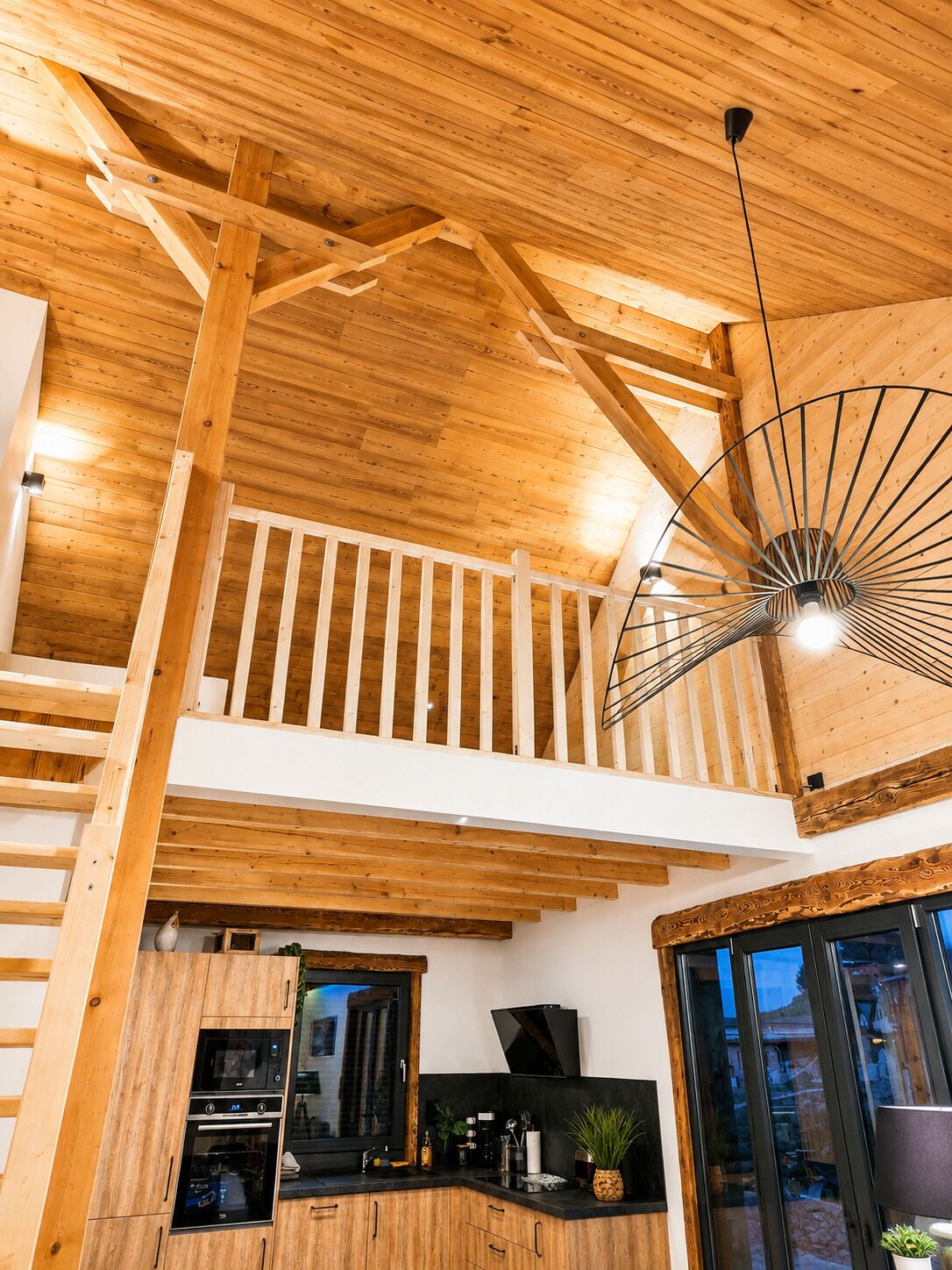 Un intérieur en bois comprenant un espace cuisine, un escalier et un ventilateur de plafond.