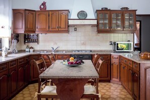 Eine Küche mit Holzausstattung, einer Granit Arbeitsplatte, einem Esstisch mit Stühlen und einer Obstschale.