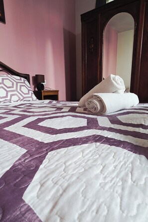 A neatly made bed with a patterned bedspread, a rolled-up towel, and a bedside table with a lamp. - Coffee baba Chefchaouen (Chefchaouen)