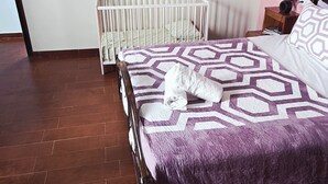 A bedroom with a bed, a crib, a painting, and a nightstand. - Coffee baba Chefchaouen (Chefchaouen)