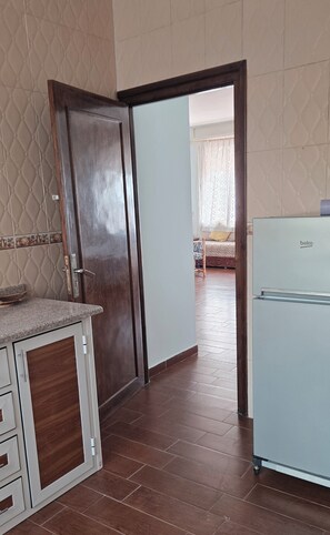 A kitchen with a refrigerator, a wooden cabinet, and a tiled floor. - Coffee baba Chefchaouen (Chefchaouen)