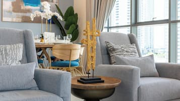 Uma sala de estar moderna com sofás cinza, uma mesa redonda de madeira e uma escultura dourada decorativa.