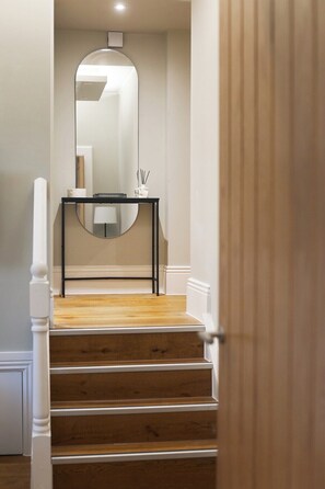 A staircase leading to a room with a mirror, a small table, and a white door. - Central Russell Square Studio Retreat (Greater London)