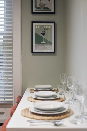 A dining table set with plates, glasses, and cutlery, with framed pictures on the wall. - Central Russell Square Studio Retreat (Greater London)