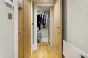 A hallway with wooden doors, a clothing rack, and a checkered towel. - Central Russell Square Studio Retreat (Greater London)
