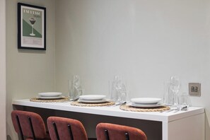 A dining table set with plates, cutlery, and glassware, with a framed menu on the wall. - Central Russell Square Studio Retreat (Greater London)