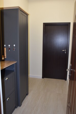 Una habitación con un armario de madera oscura, un pequeño estante de madera y una puerta oscura cerrada.