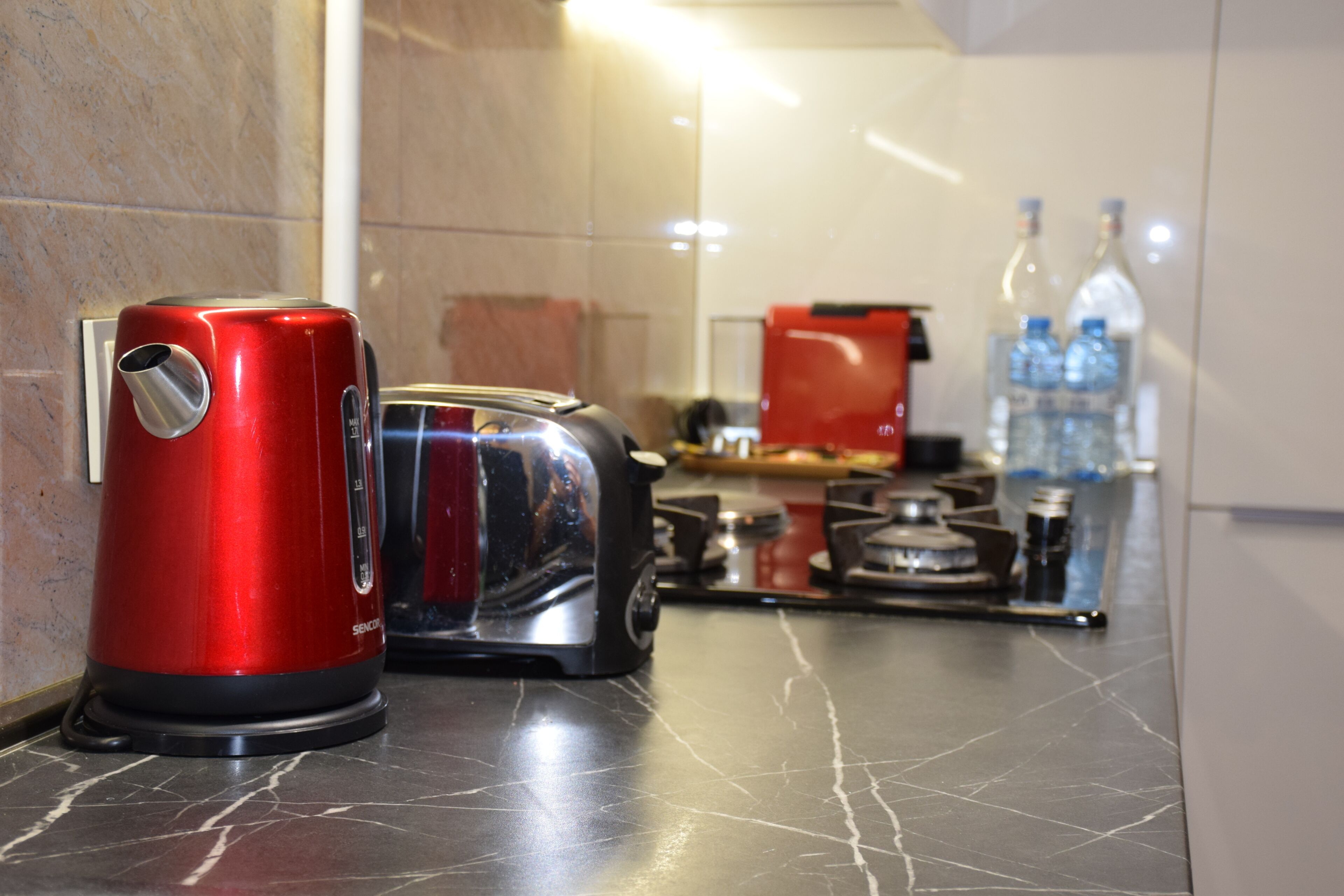 A kitchen with a red electric kettle, a toaster, and a red coffee maker on the counter.