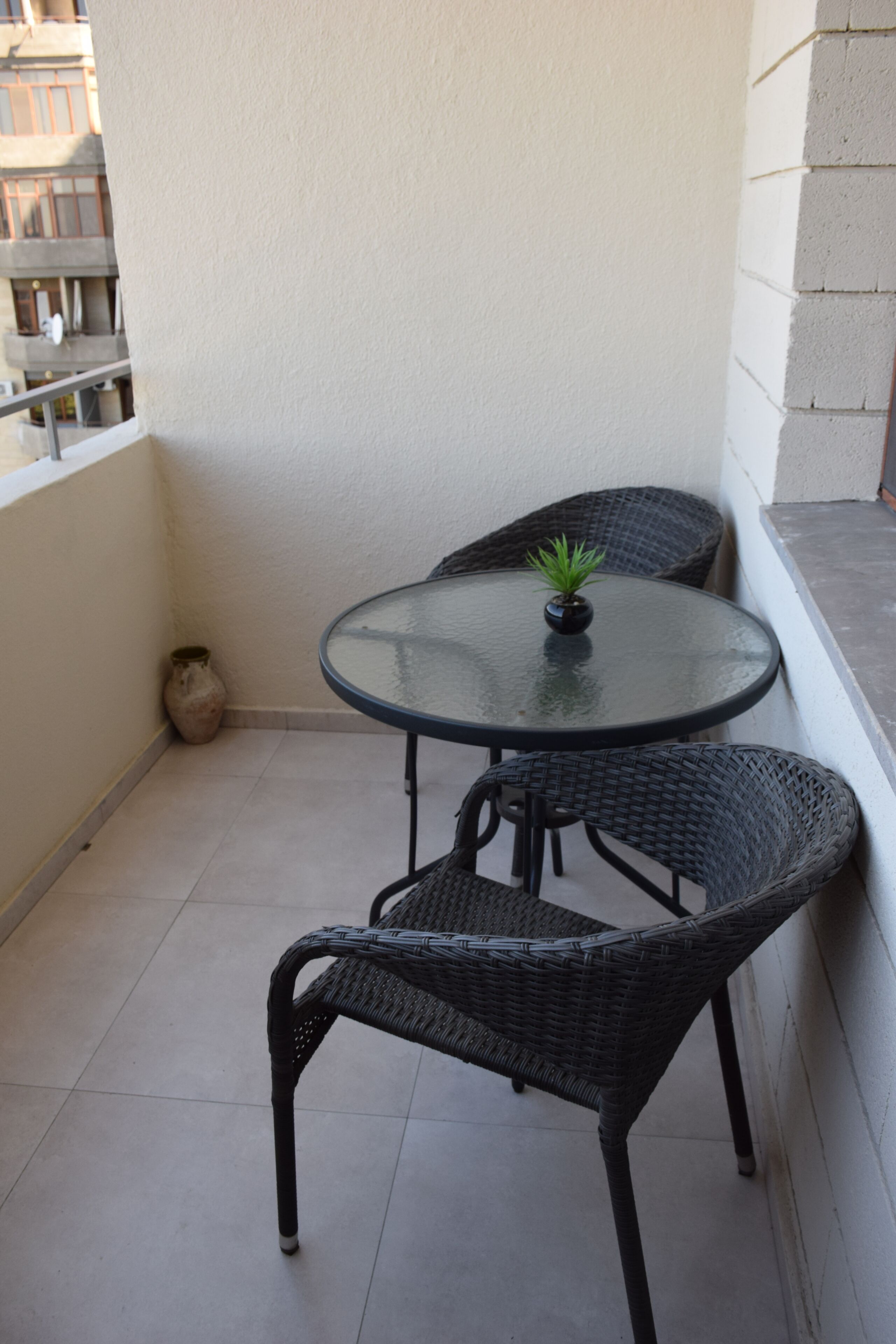 Un pequeño espacio al aire libre con una mesa redonda y dos sillas de mimbre.