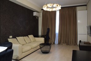 Una sala de estar moderna con un sofá, una mesa de centro y un televisor sobre un mueble.