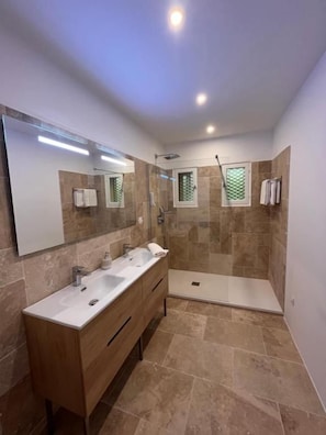 Un bagno moderno con una vasca a doppio lavabo, una cabina doccia e un grande specchio.