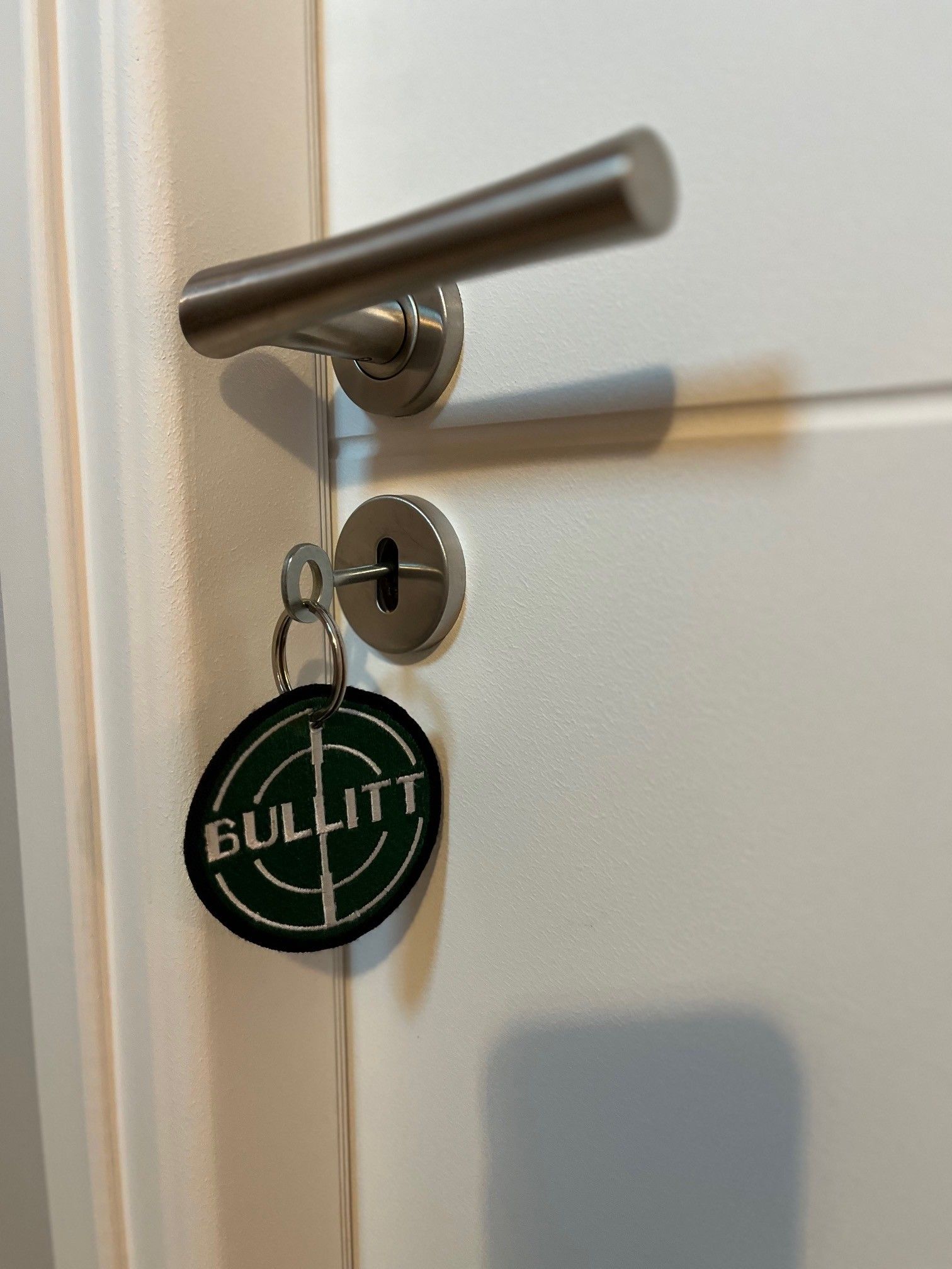 Una puerta con un ojo de cerradura y un llavero con la palabra 'BULLITT'.