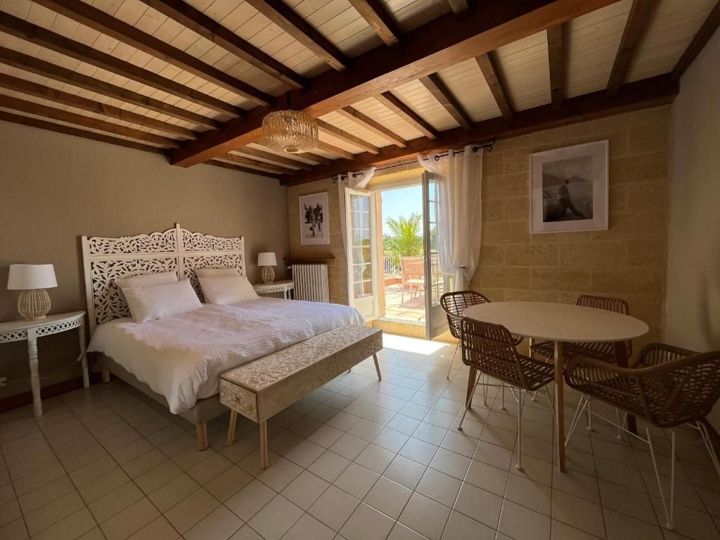 Een slaapkamer met een bed, nachtkastjes, een stoel, een tafel en uitzicht op het omliggende landschap.