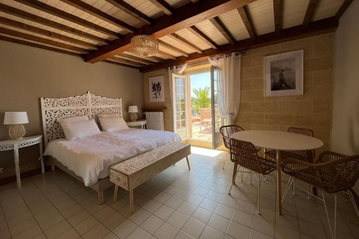 Una camera da letto con un letto, comodini, una sedia, un tavolo e vista sull'esterno.