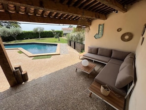Un espacio exterior cubierto con piscina, un sofá y una pequeña mesa.