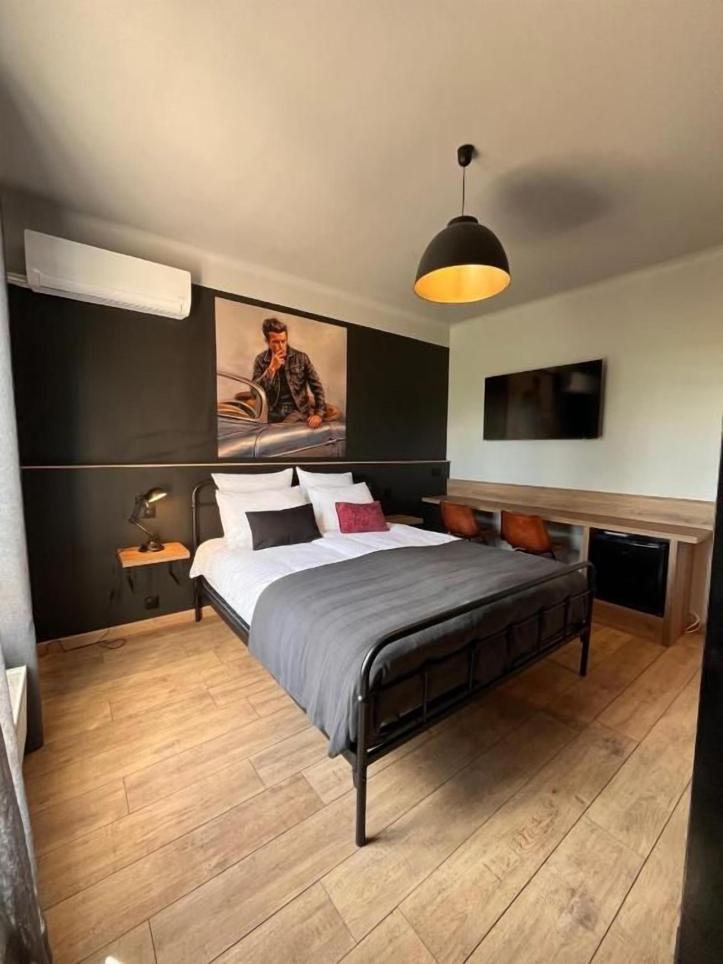 A modern bedroom with a bed, bedside table, lamp, and artwork on the wall.