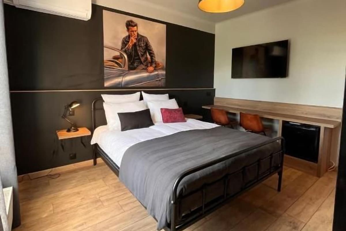 Una camera da letto moderna con un letto, un comodino, una lampada e un'opera d'arte appesa al muro.