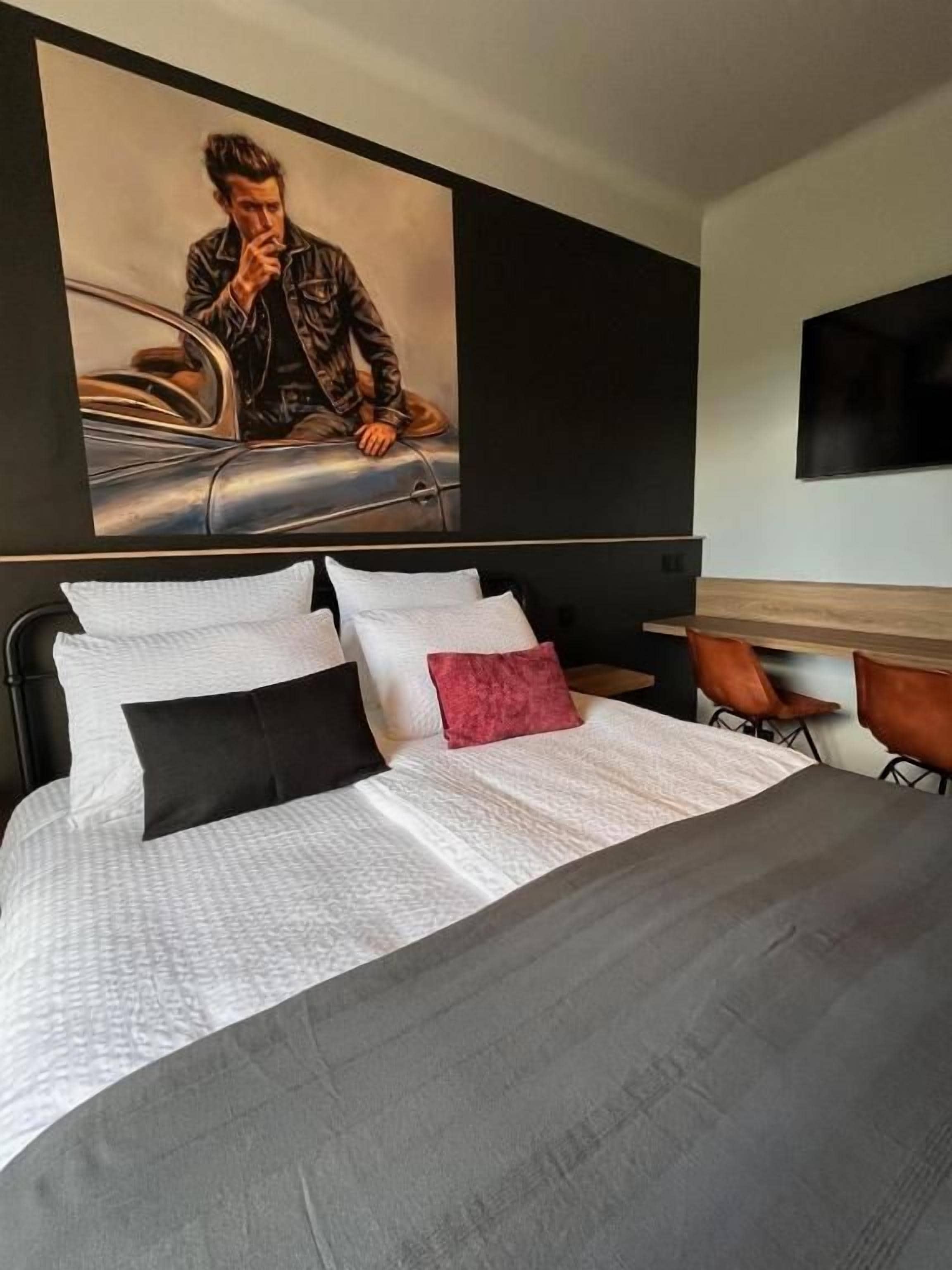 Une chambre d’hôtel avec un grand lit, un tableau au mur et un bureau avec une chaise.