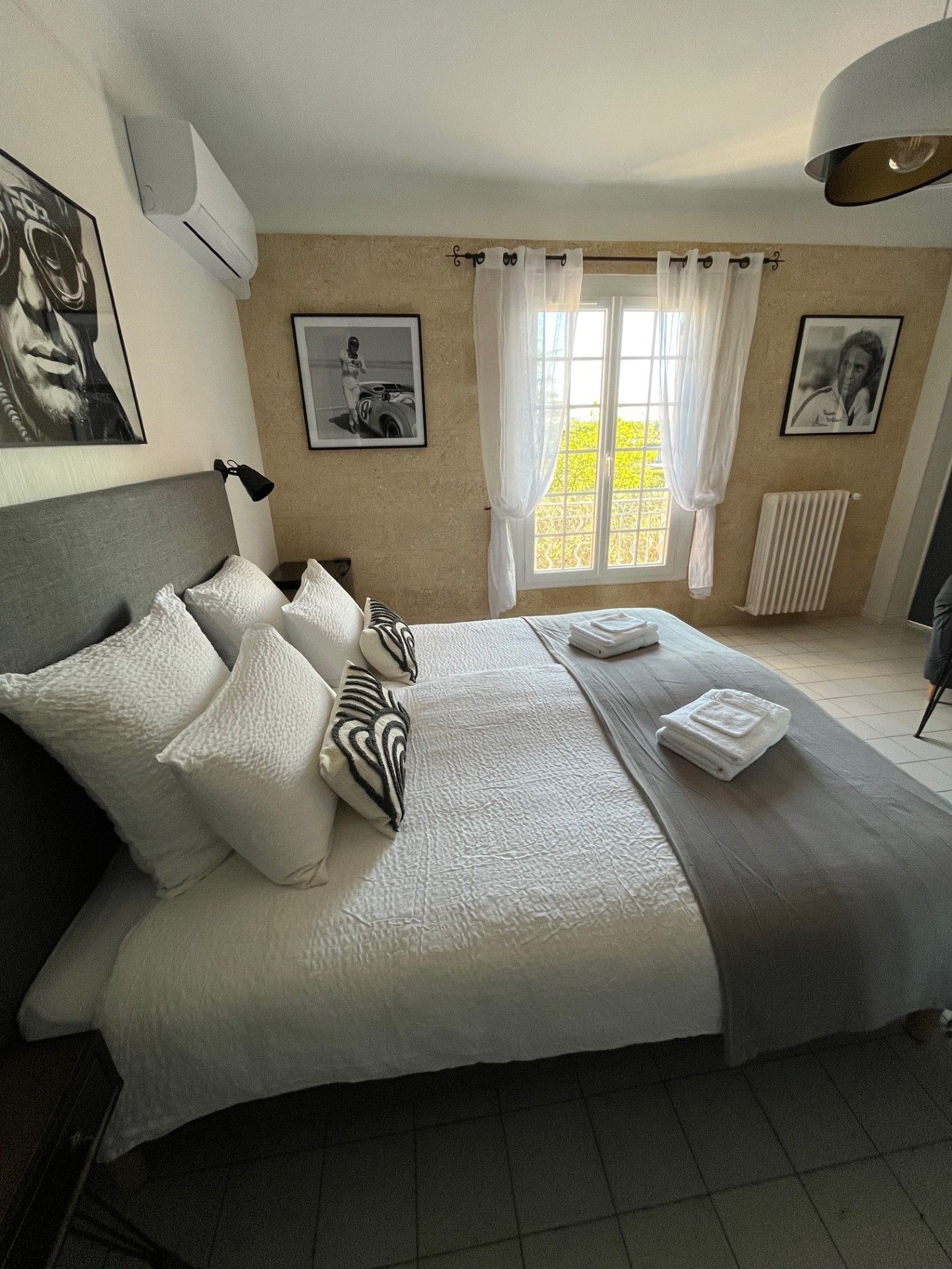 Una habitación de hotel con una cama grande, un ventanal con cortinas y obras de arte en las paredes.
