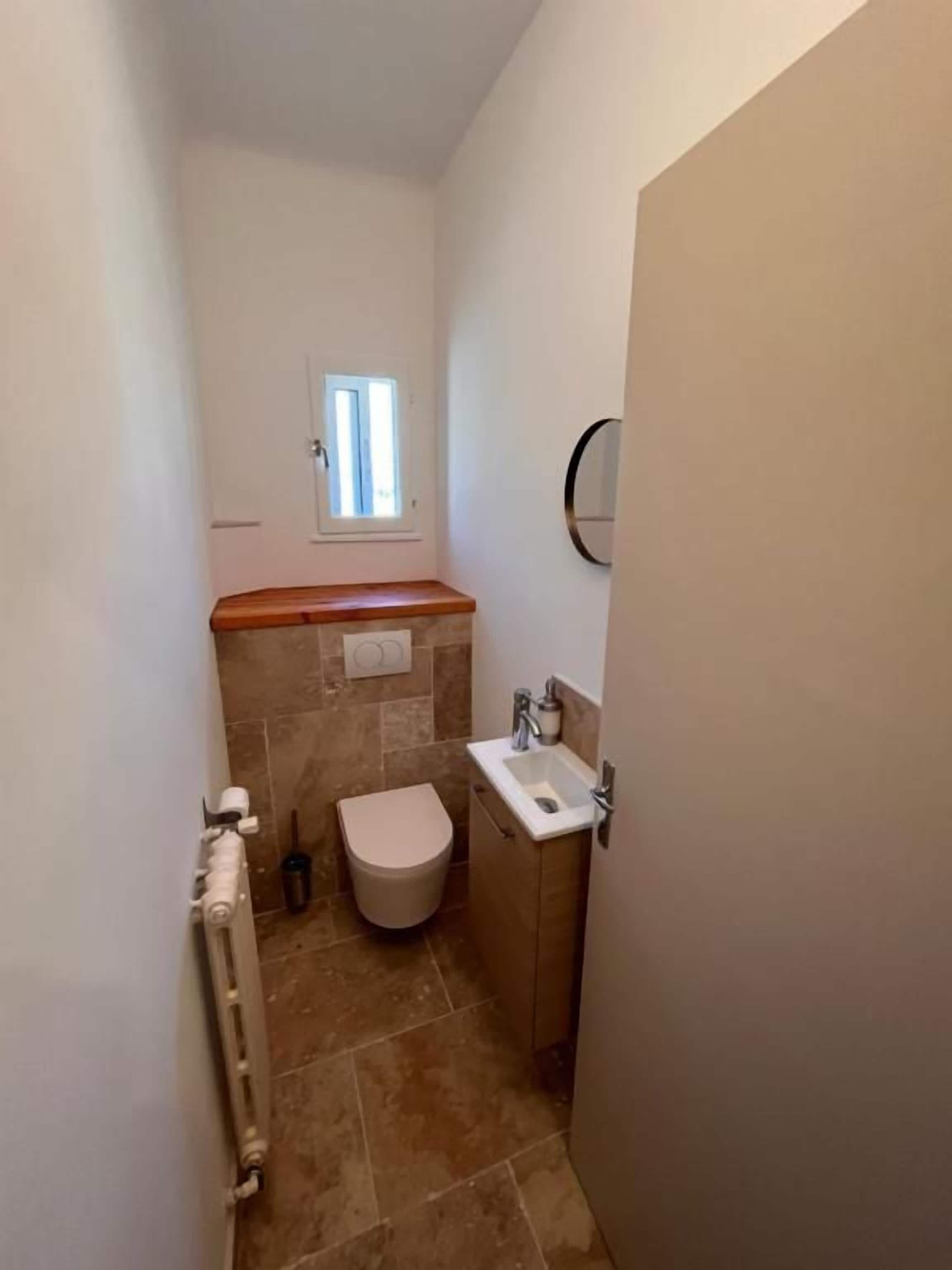 A small bathroom with a toilet, sink, and a window.