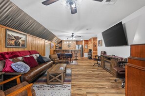 Ein großzügiger Wohnbereich mit einer Ledersofa, Holzboden und einem großen Flachbildfernseher an der Wand.