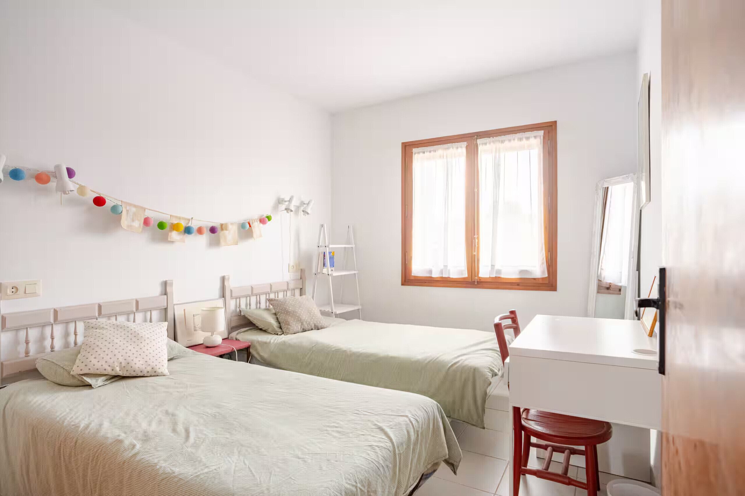 Une chambre avec deux lits, un bureau et une chaise.