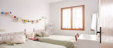 Un dormitorio con dos camas, un escritorio y una silla.