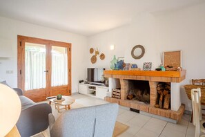 Ein Wohnzimmer mit Fernseher, Kamin und Essbereich mit Tisch und Stühlen.