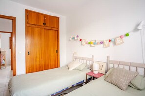 Ein Schlafzimmer mit zwei Betten, einem Holzschrank und einer Wanddekoration aus Buchstaben, die das Wort 'LOVE' bilden.