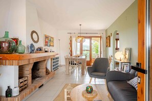 A living room with a fireplace, dining area, and a sofa. - CAN BONIC: Charming house with a shared swimming pool in the heart of the Empordà (Bellcaire d´Empordà)