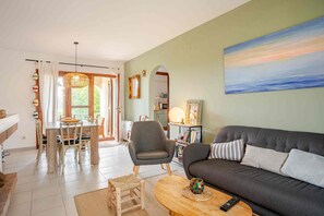 Ein Wohnzimmer mit grauem Sofa, einem Holztisch und einem Essbereich mit Esstisch und Stühlen.