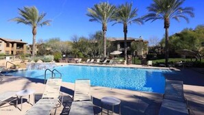 A swimming pool with lounge chairs and palm trees. - Villa Bella Monte 1 Bedroom Condo (Phoenix)