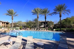 A swimming pool with lounge chairs and palm trees. - Villa Bella Monte 1 Bedroom Condo (Phoenix)
