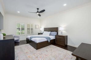 Ein Schlafzimmer mit einem Bett, Nachttischen, einem Deckenventilator und einem Fenster mit Rollläden.