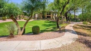 A landscaped outdoor area with a pathway, neatly trimmed grass, and a variety of trees. - Villa Bella Monte 1 Bedroom Condo (Phoenix)