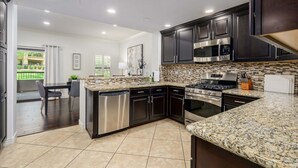 A modern kitchen with dark cabinets, stainless steel appliances, and a granite countertop. - Villa Bella Monte 1 Bedroom Condo (Phoenix)