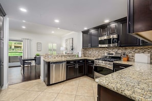 A modern kitchen with dark cabinets, stainless steel appliances, and a granite countertop. - Villa Bella Monte 1 Bedroom Condo (Phoenix)