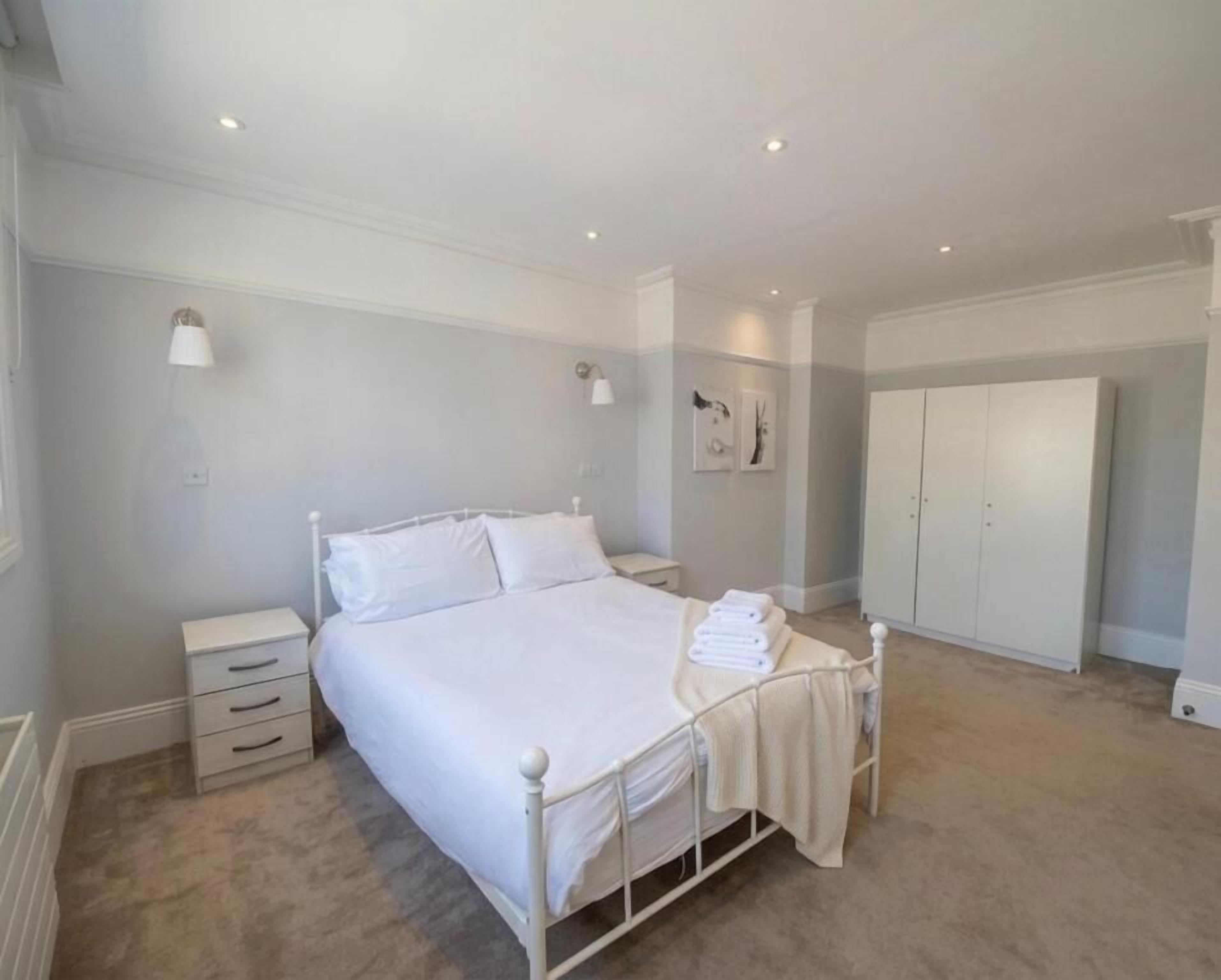 Un dormitorio con cama, mesitas de noche, armario y suelo alfombrado.