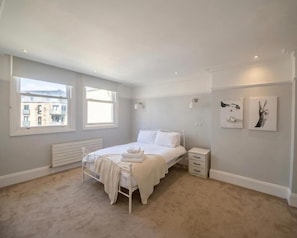 Ein Schlafzimmer mit einem Bett, Nachttischen, einem Heizkörper und Bildern an der Wand.