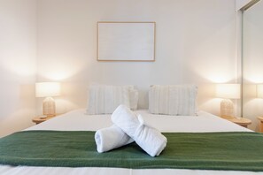 A hotel room with a neatly made bed, two pillows, a green throw blanket, and two bedside lamps. - Modern living, prime location, everything within easy reach - Broadbeach stay. (Broadbeach)
