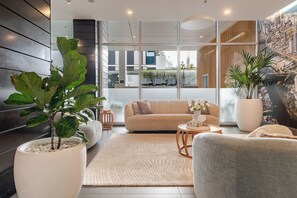 A modern living room with a sofa, a coffee table, and a large potted plant. - Modern living, prime location, everything within easy reach - Broadbeach stay. (Broadbeach)
