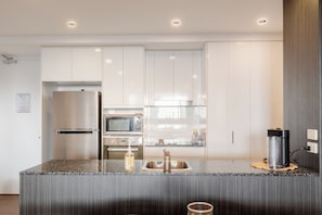 A modern kitchen with stainless steel appliances, a granite countertop, and recessed ceiling lighting. - Modern living, prime location, everything within easy reach - Broadbeach stay. (Broadbeach)