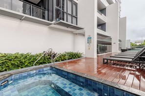 A rooftop swimming pool with a wooden deck, surrounded by lush greenery and modern architecture. - Modern living, prime location, everything within easy reach - Broadbeach stay. (Broadbeach)